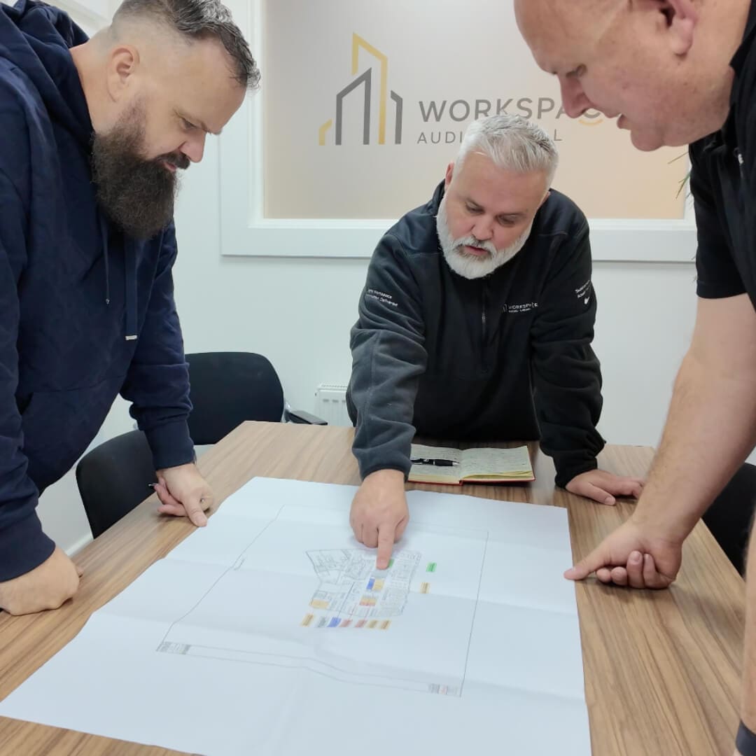 group of men standing around a wooden table